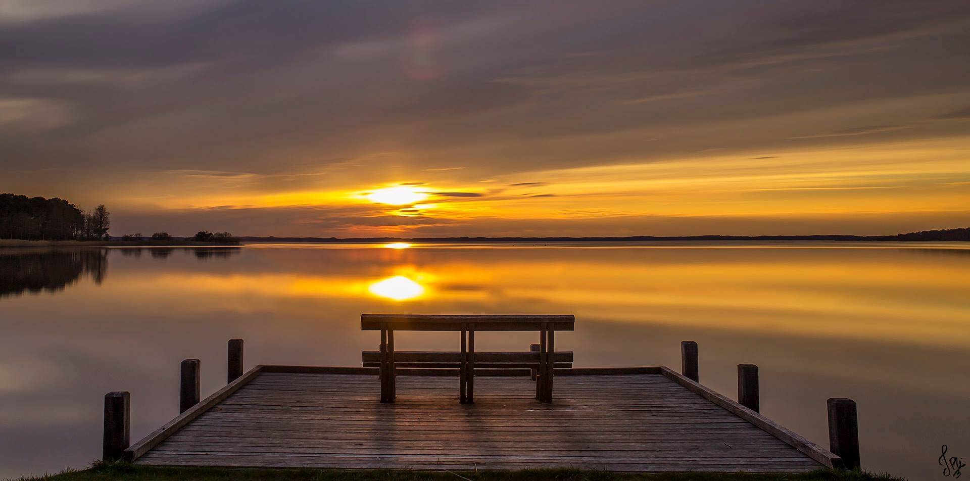 Un banc sur un ponton au soleil couchant au lac de Cazaux